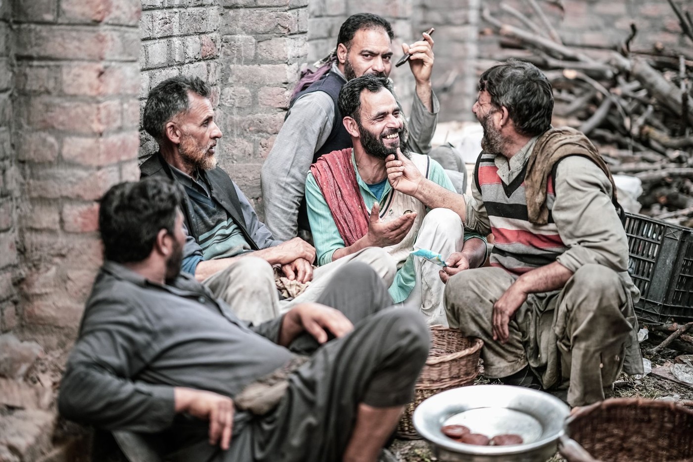 Un grupo de hombres sentados y riendo juntos al aire libre, transmitiendo amistad y comunidad.