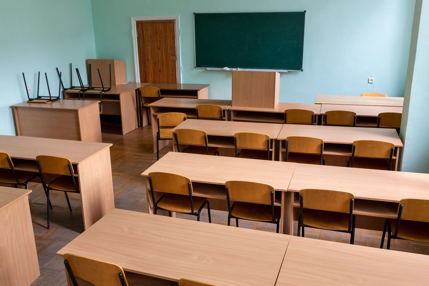 Un aula vacía con filas de pupitres de madera y una pizarra verde, que crea un ambiente tranquilo y propicio para el aprendizaje.