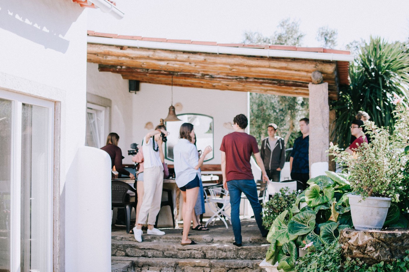 Un grupo de jóvenes socializando al aire libre en un patio soleado, rodeados de vegetación.