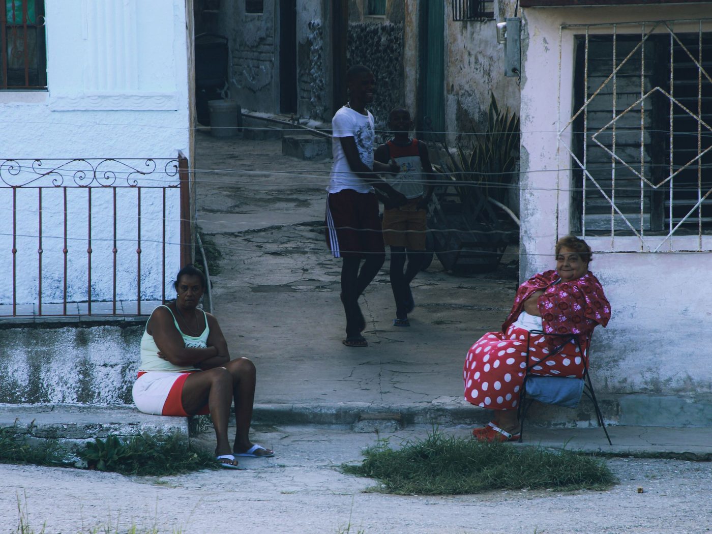 Dos mujeres sentadas en una calle residencial de casas sencillas