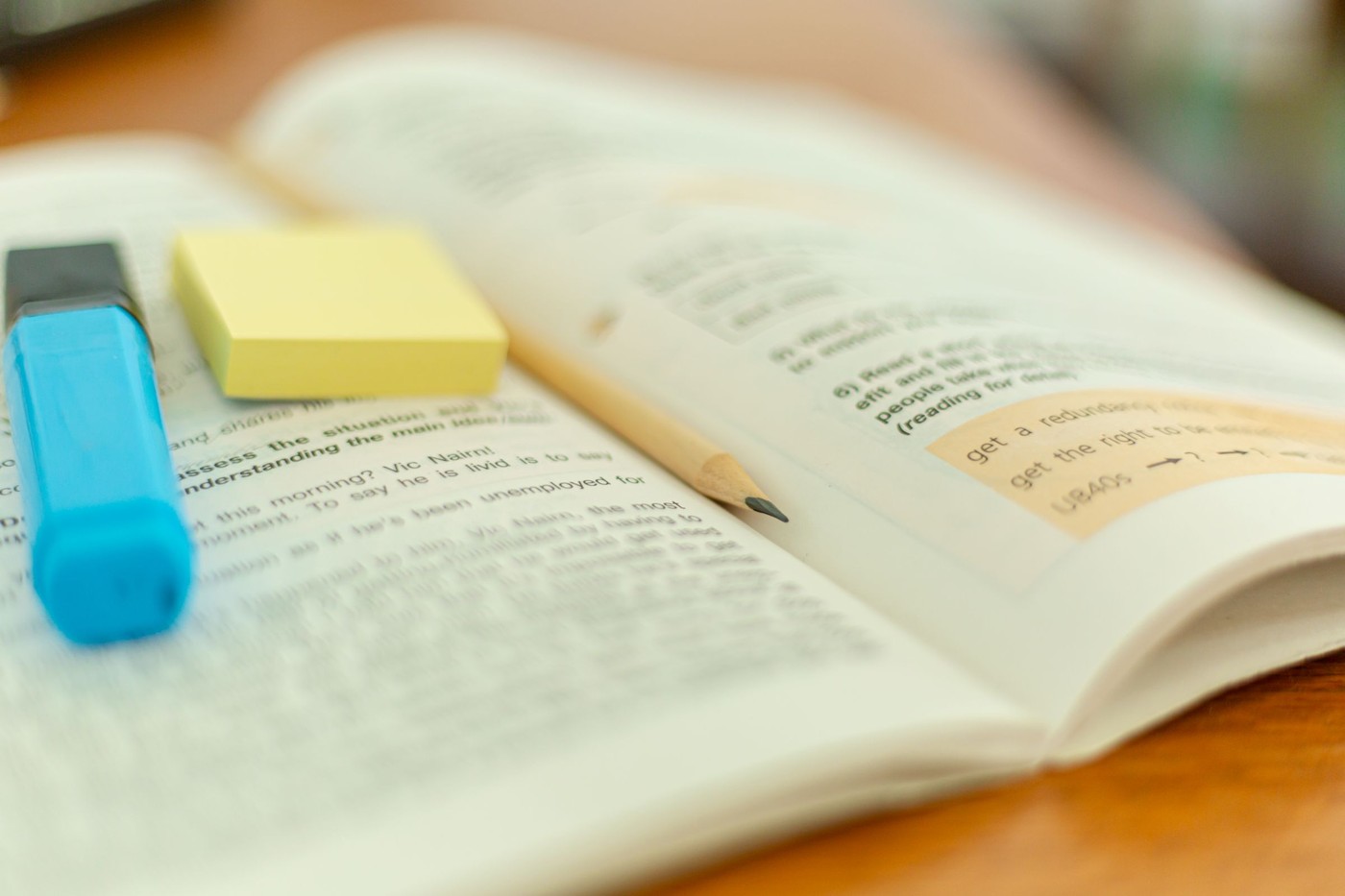 Primer plano de un libro abierto con un resaltador y notas adhesivas para referencia de estudio.