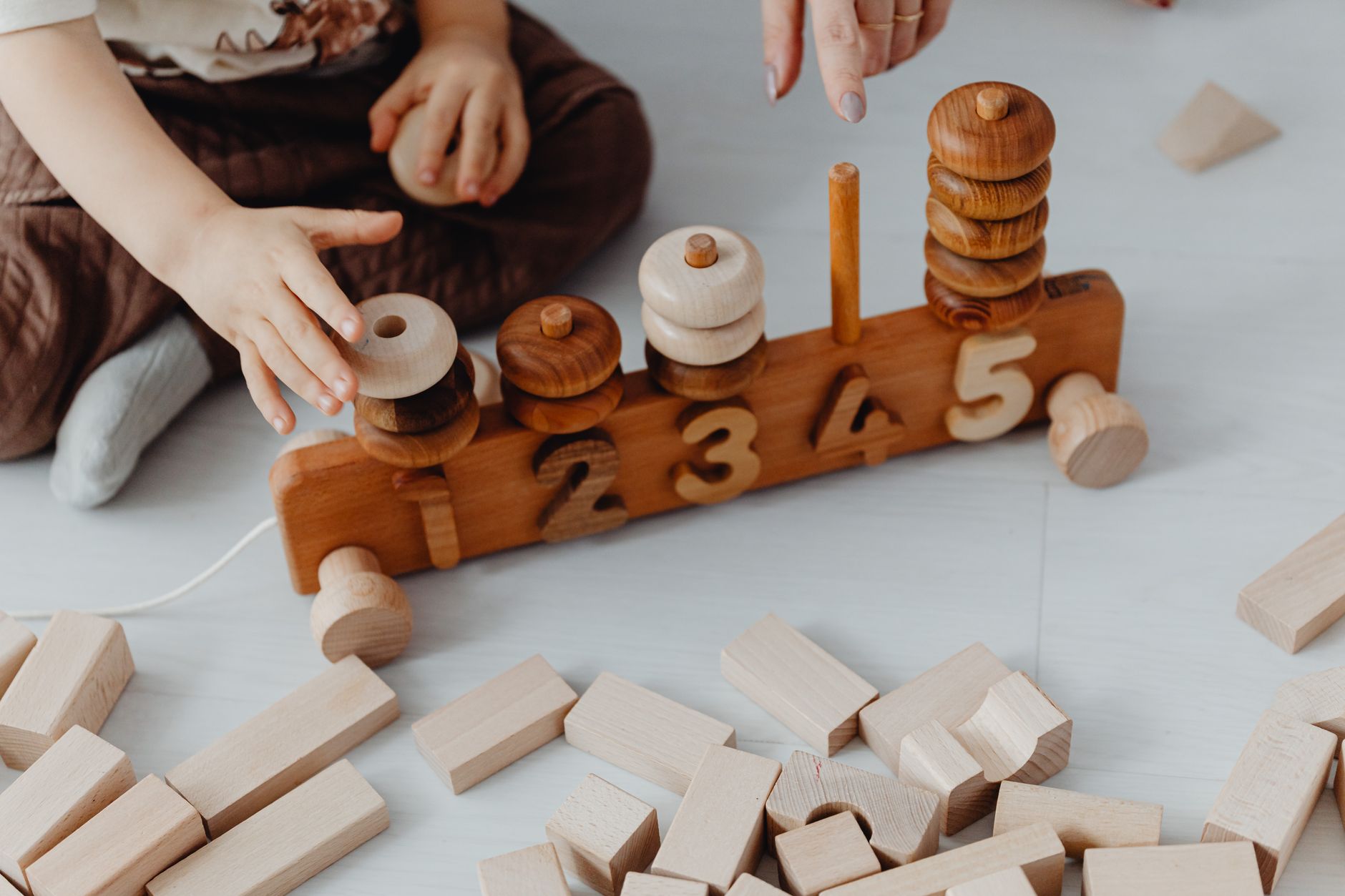 Manos infantiles manipulando un contador de madera con los números del 1 al 5 sobre una mesa
