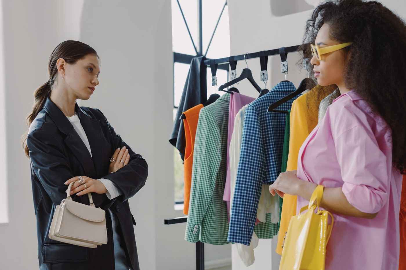 Dos mujeres ojeando estantes de ropa colorida en una boutique moderna.
