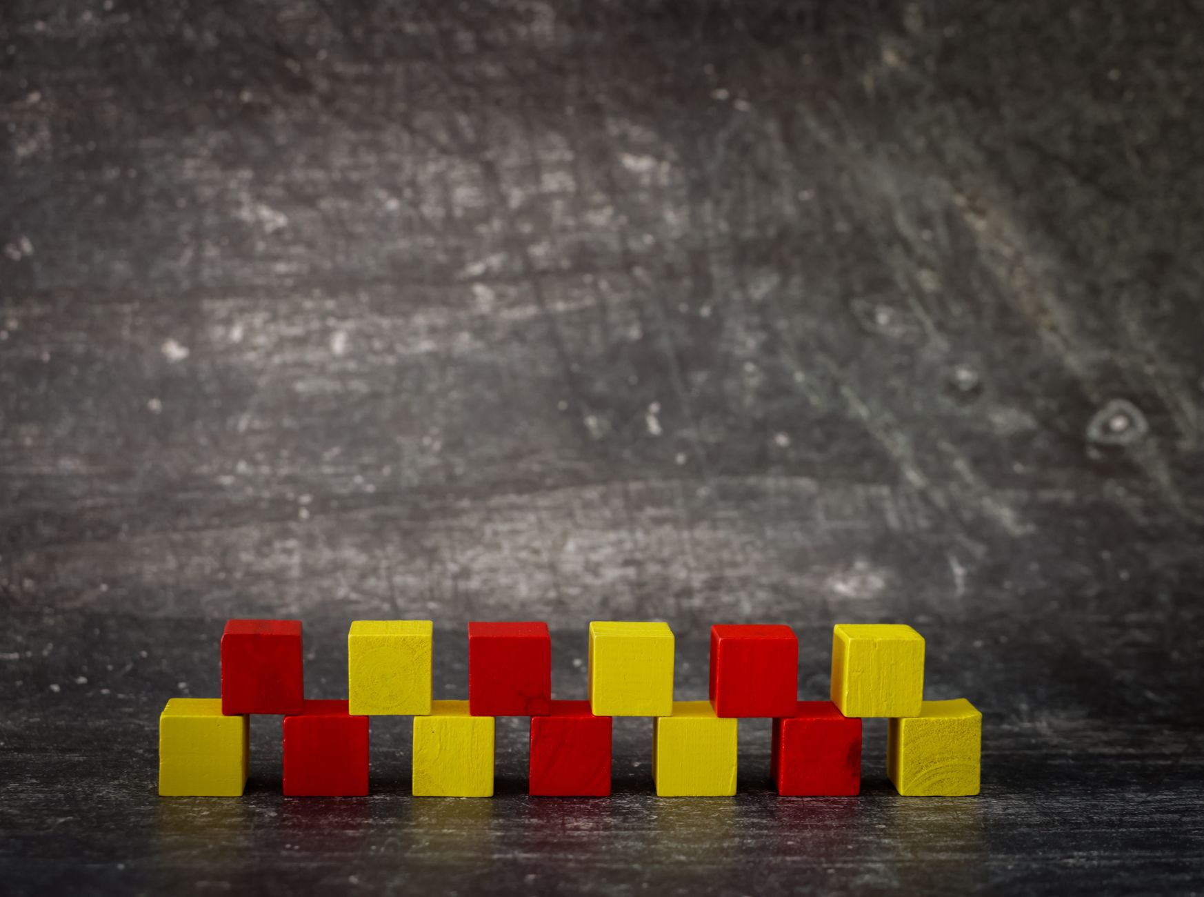 Bloques cúbicos de colores apilados de forma irregular sobre un fondo gris texturizado