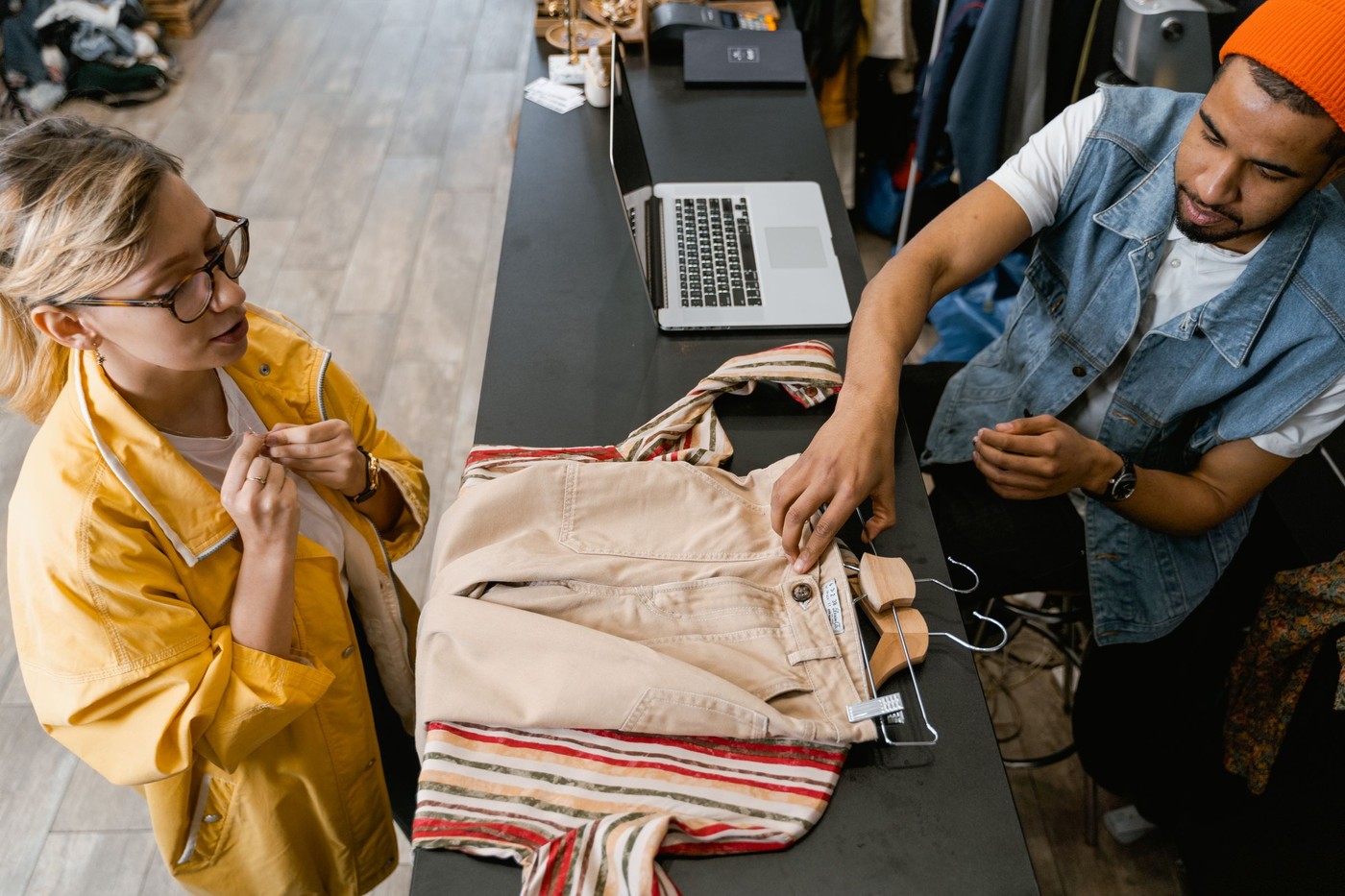 Un hombre y una mujer en un mostrador de boutique discutendo una compra de ropa.
