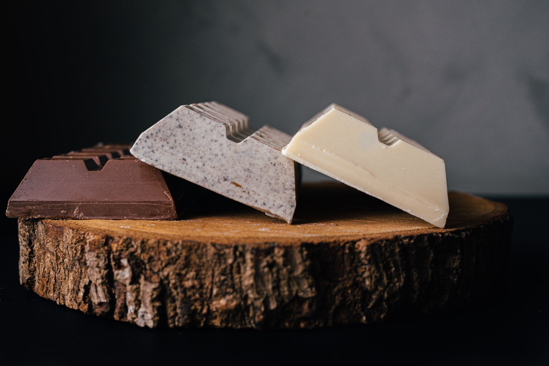 Trozos de chocolate blanco, con leche y oscuro sobre una rodaja de tronco