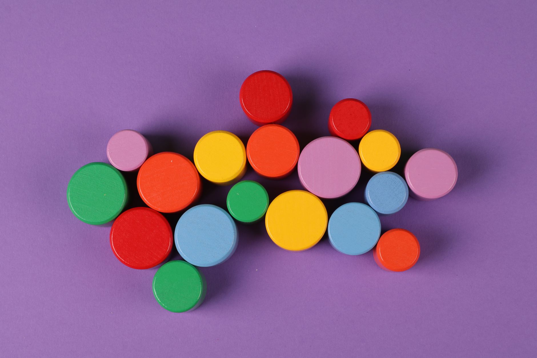 Fichas circulares de colores dispersas sobre un fondo lila