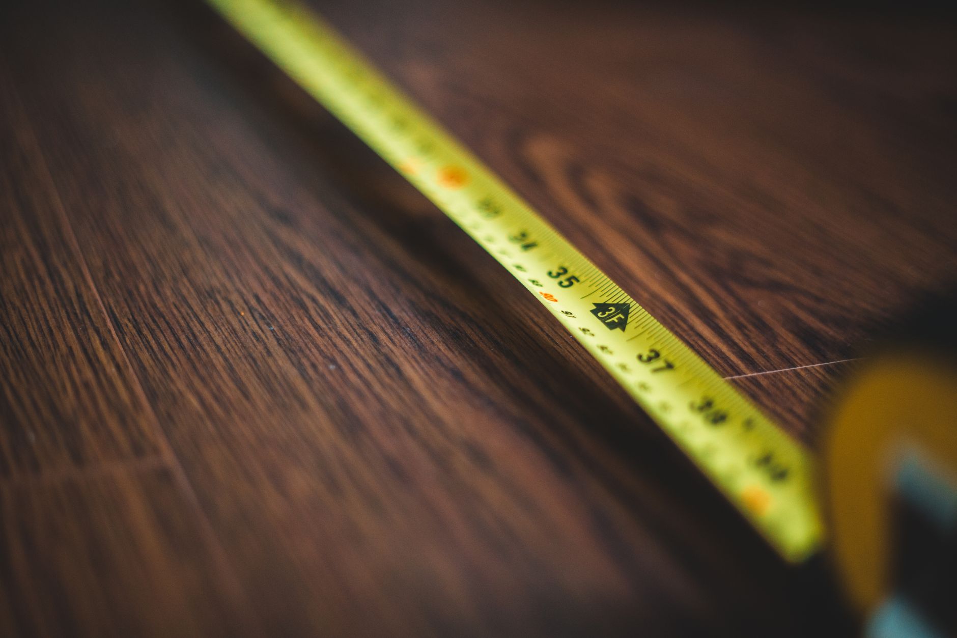 Cinta métrica amarilla extendida sobre un suelo de madera oscura