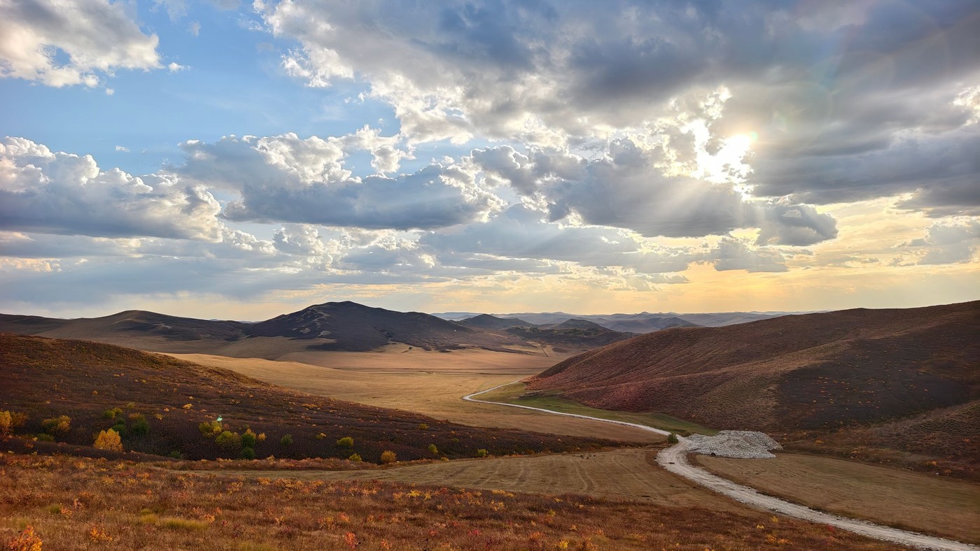 Vista cautivadora de colinas ondulantes bajo un cielo dramático al atardecer, resaltando la belleza de la naturaleza.