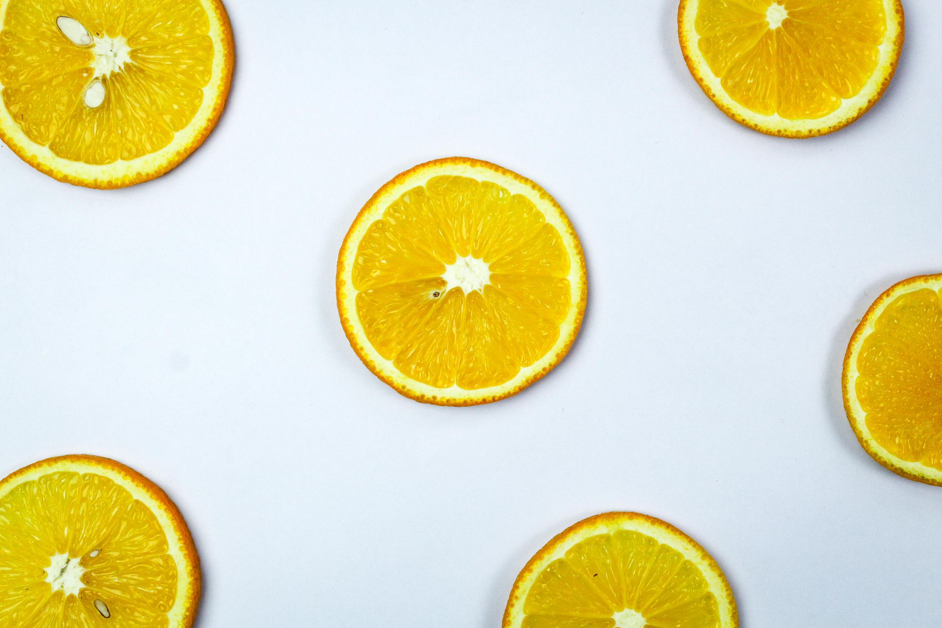 Rodajas de naranja repartidas sobre un fondo blanco