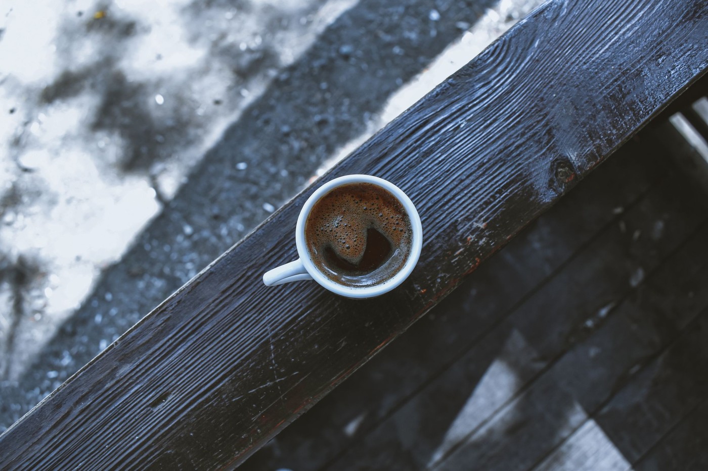 Vista aérea de una taza de café de cerámica sobre una mesa de madera antigua, que ofrece un ambiente rústico.