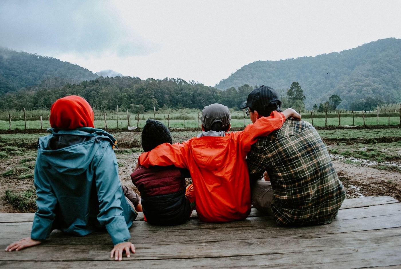 Cuatro personas de una familia contemplan juntas el paisaje rural con montañas al fondo.