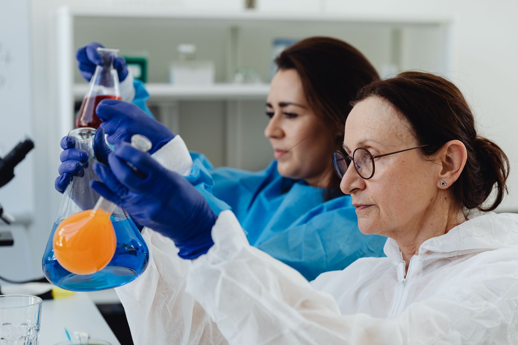 dos científicas trabajando en un laboratorio con soluciones químicas en frascos