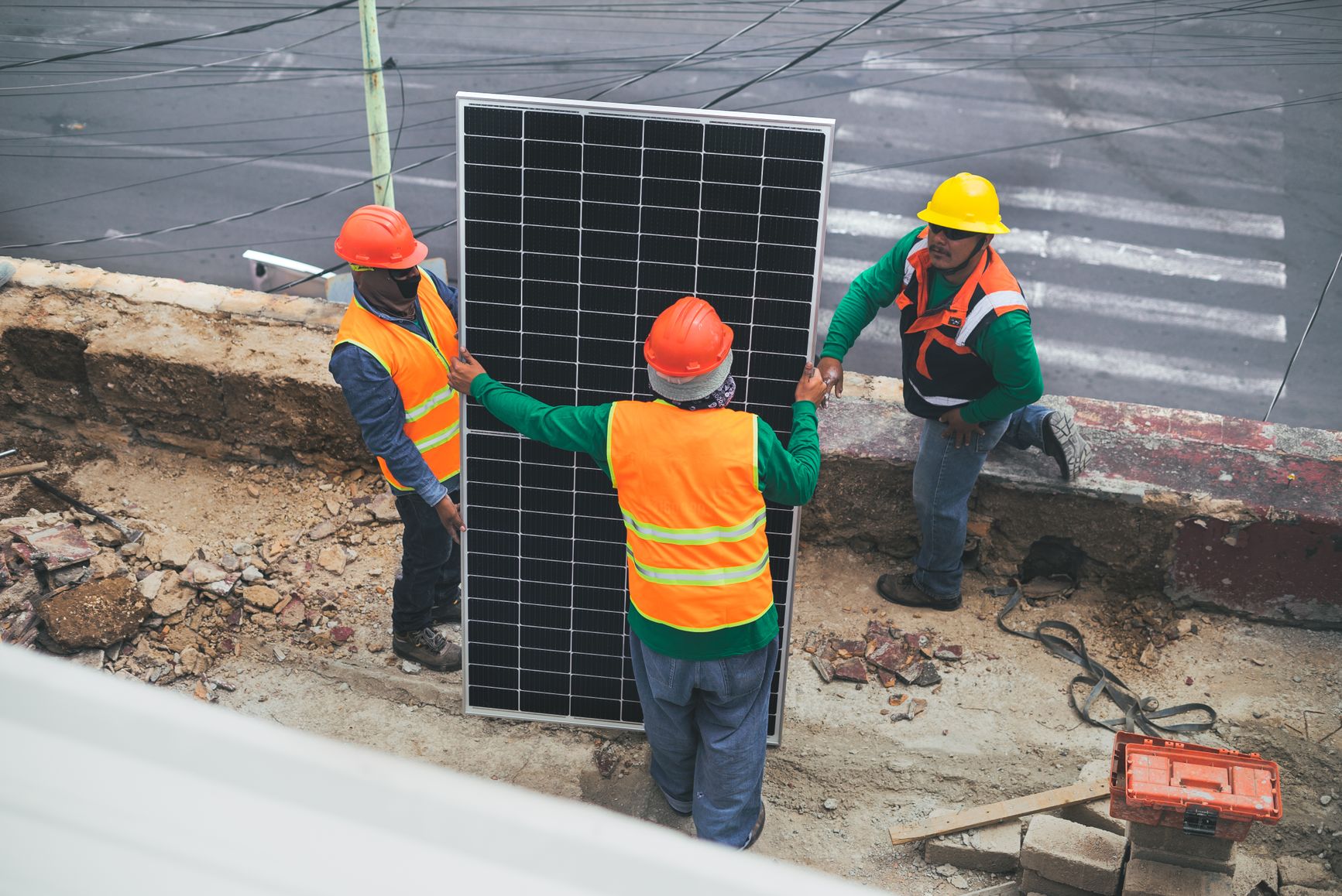 Trabajadores con equipo de protección personal instalan paneles solares en una obra.