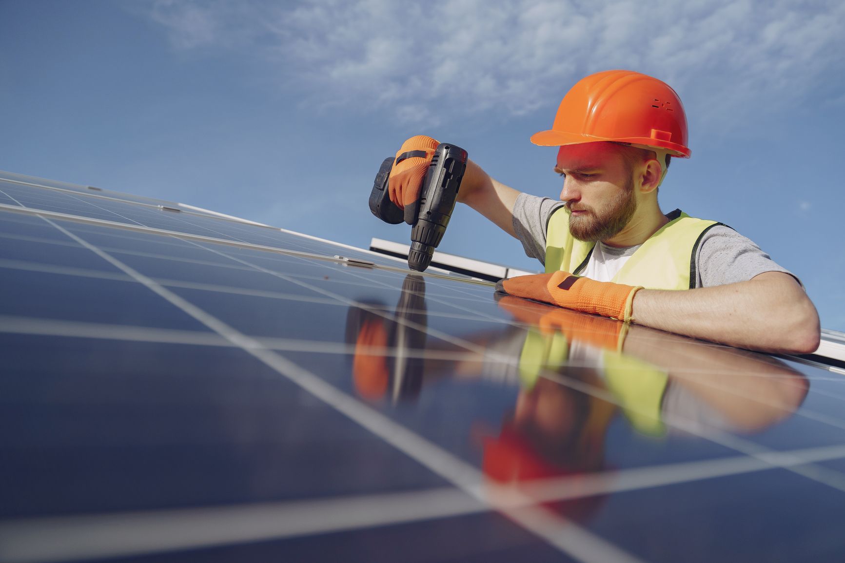 Ingeniero con casco y equipo de seguridad instalando un panel solar al aire libre.