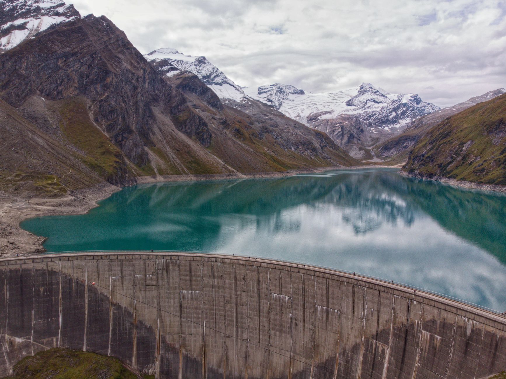 Un paisaje montañoso con una presa reflejada en un lago tranquilo.