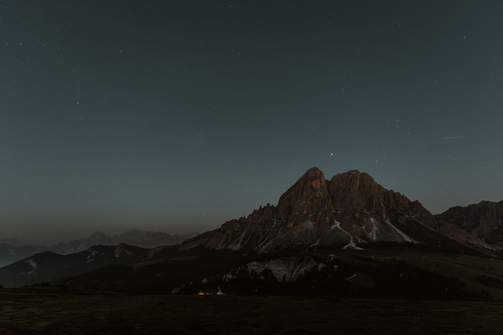 cielo estrellado y una gran masa rocosa en una fotografía nocturna de larga exposición en la montaña