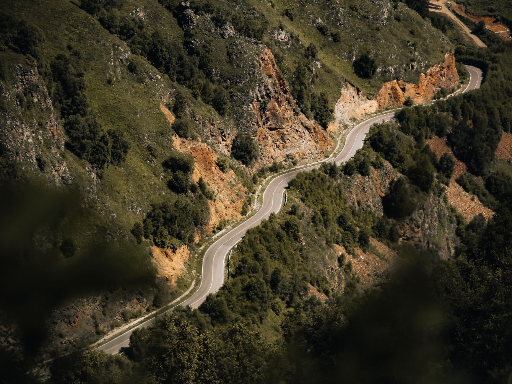 vista aérea de una carretera de montaña que sube en curvas por una ladera rocosa cubierta de vegetación