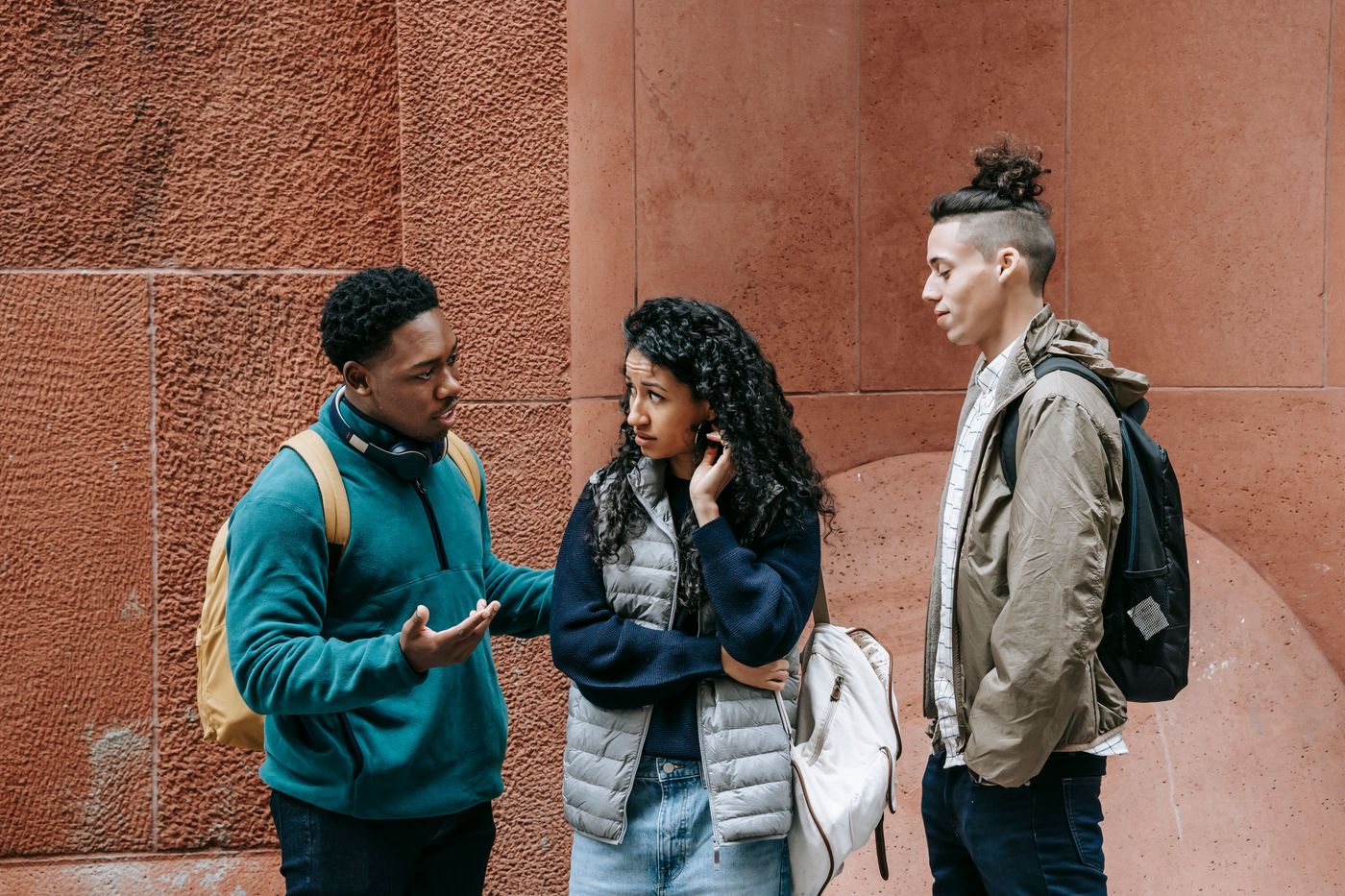 Tres estudiantes conversan de pie en una calle de su comunidad.
