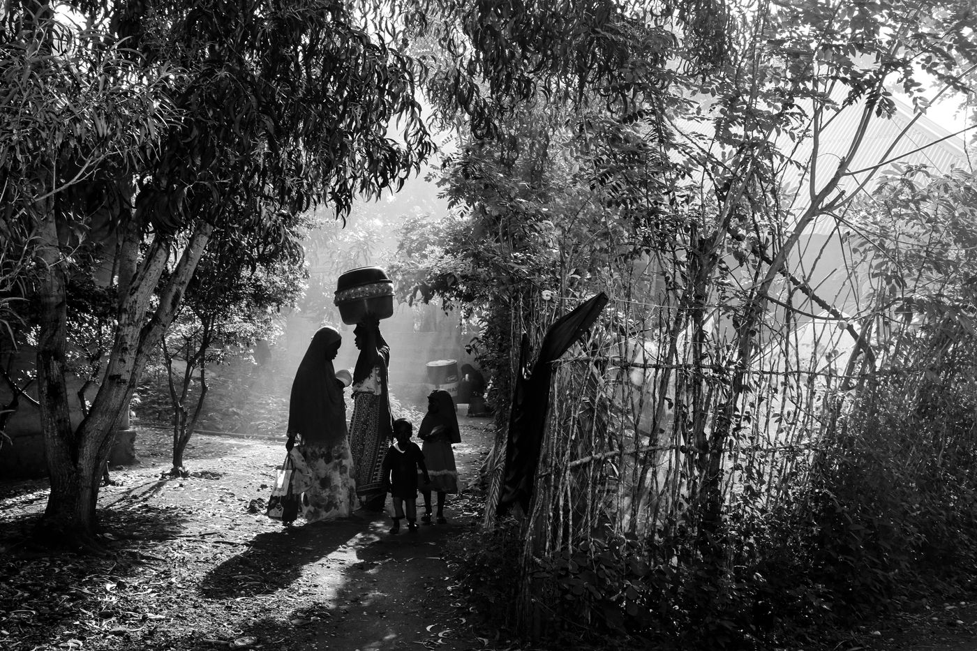 Una familia camina con sus pertenencias por un camino de tierra.