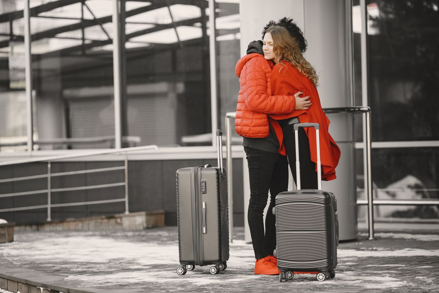 dos personas se abrazan al despedirse junto a sus maletas antes de viajar