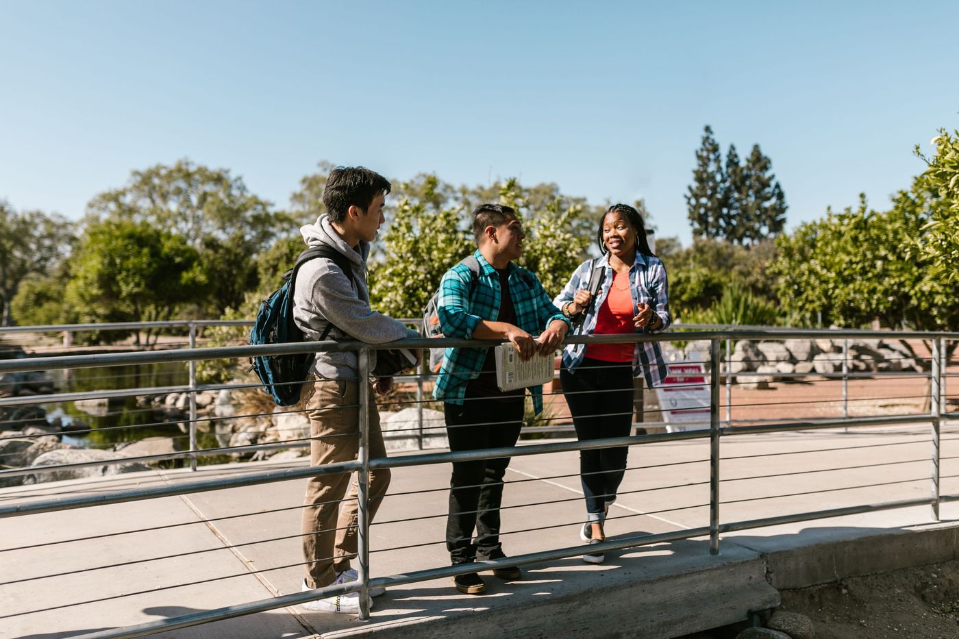 tres estudiantes conversan de pie en el patio de su centro educativo