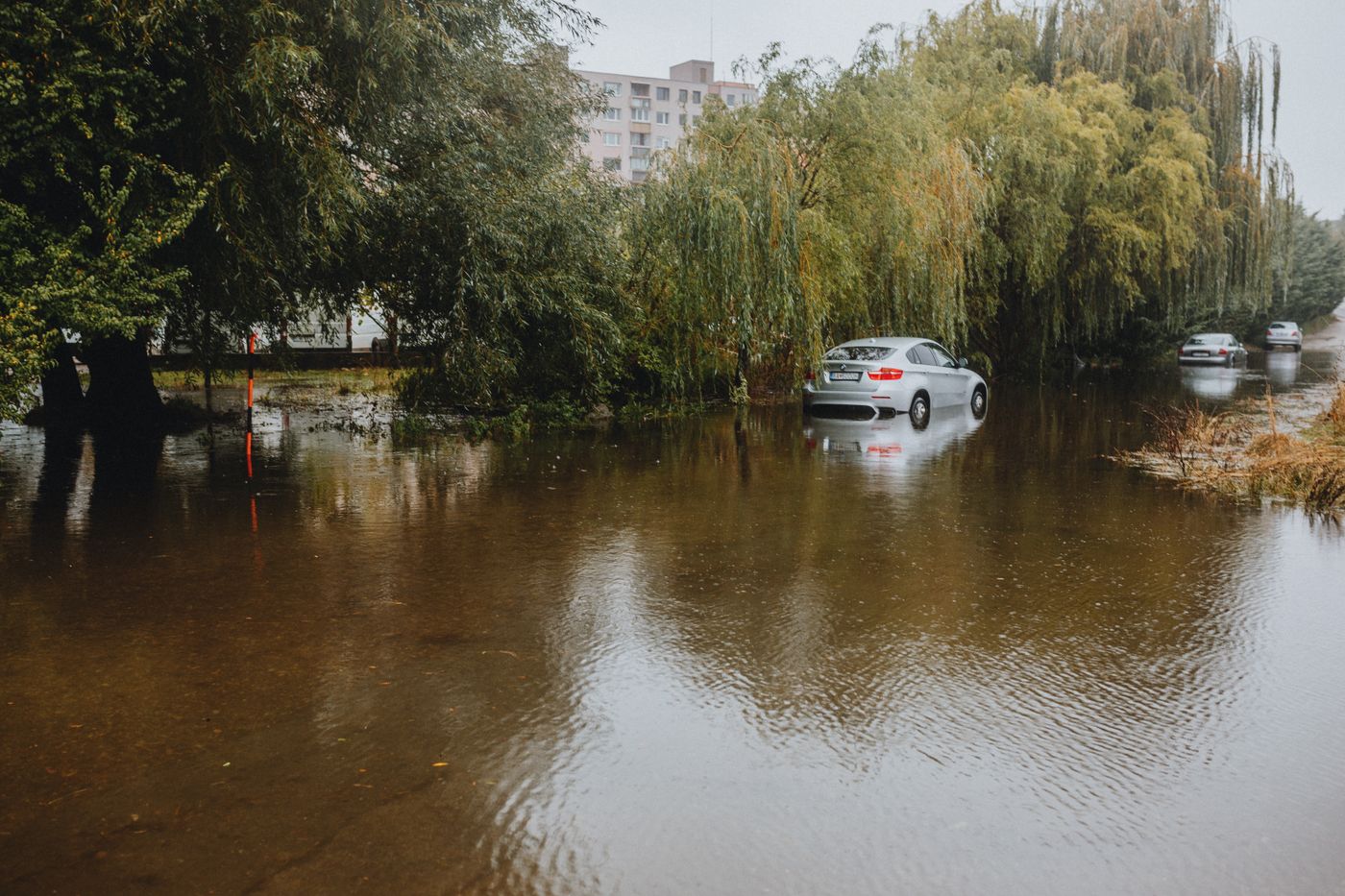 un automóvil rodeado de agua en una calle inundada
