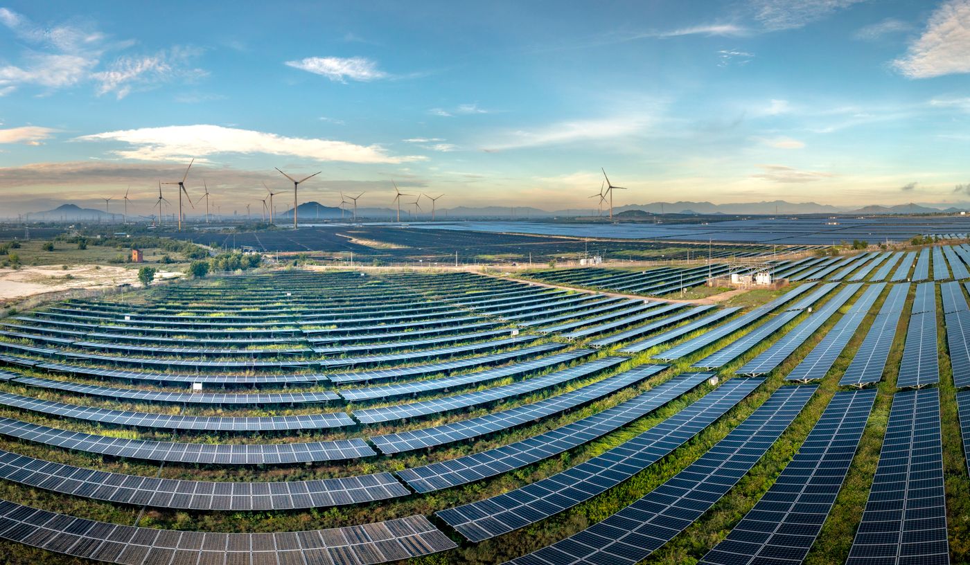una planta solar con turbinas de viento al fondo