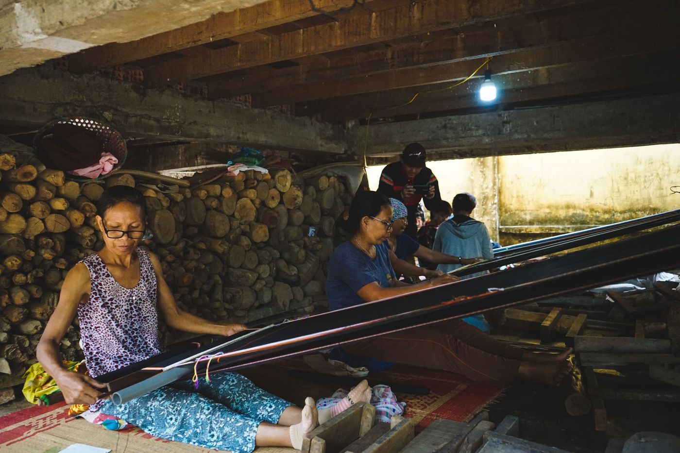 dos mujeres tejen alrededor de un telar en un taller artesanal