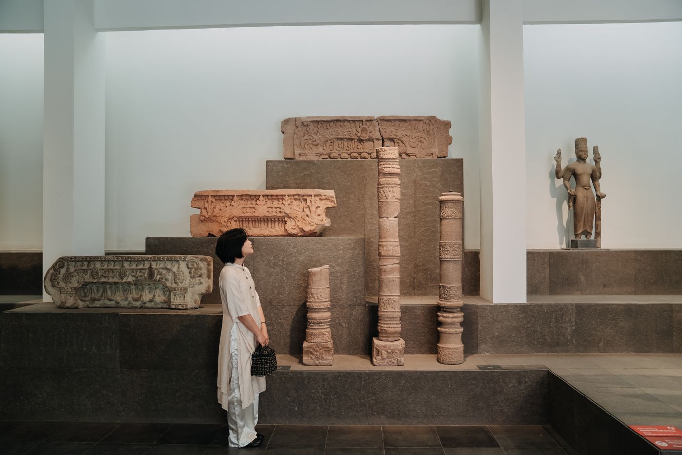una mujer observa de espaldas unos bloques de piedra antigua en una sala de museo