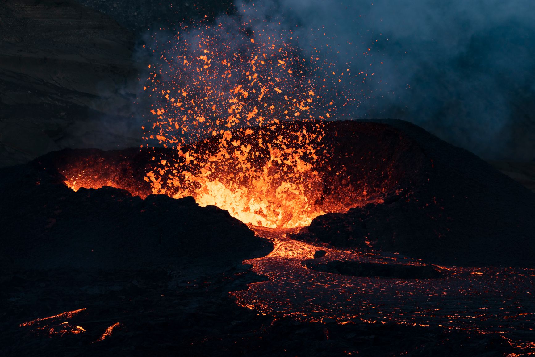 Una erupción volcánica nocturna con lava incandescente saliendo del cráter