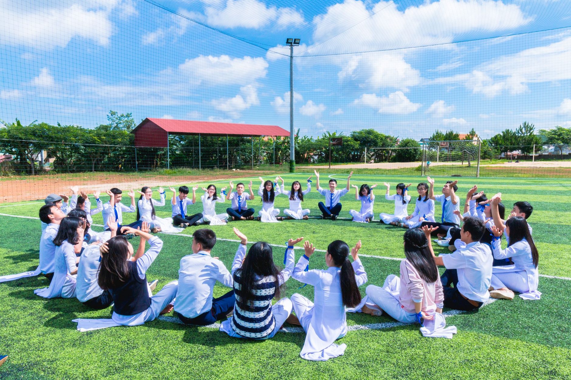 Estudiantes de secundaria sentados en círculo en la cancha del colegio durante una actividad grupal