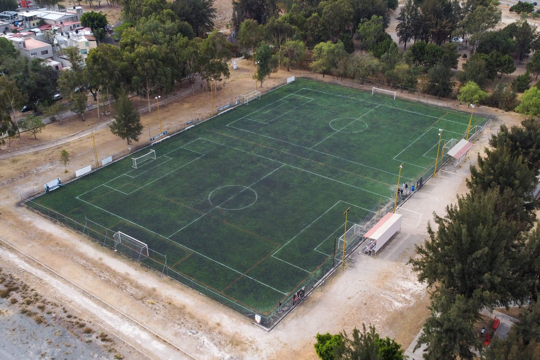 Cancha de fútbol con sus porterías y sus redes, rodeada de árboles, vista desde lo alto