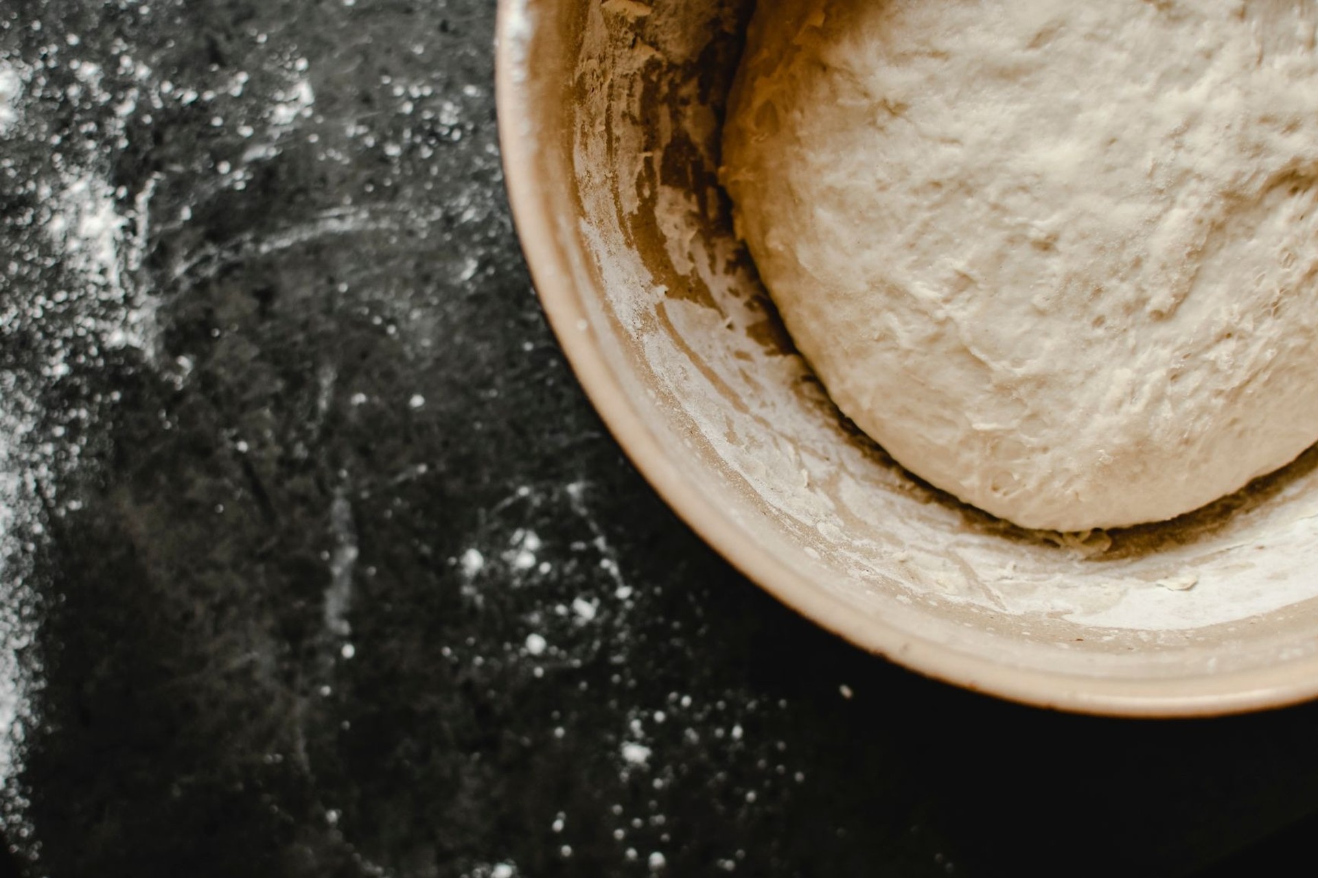 Masa de pan enharinada dentro de un bol de cerámica