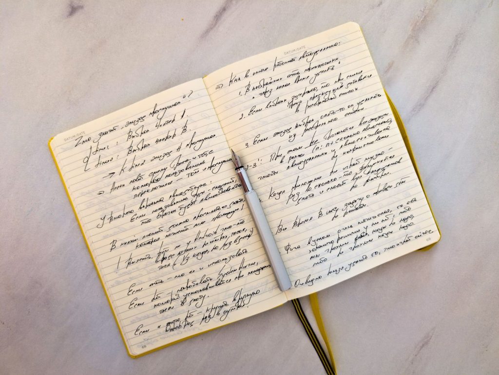 Mano escribiendo con bolígrafo sobre un cuaderno abierto