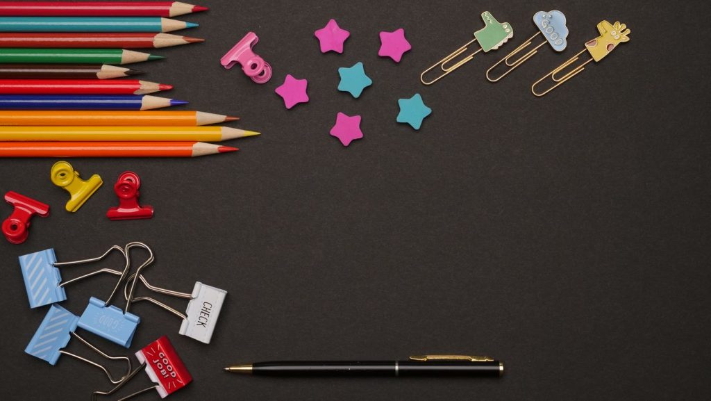 Lápices de colores junto a clips sobre una mesa