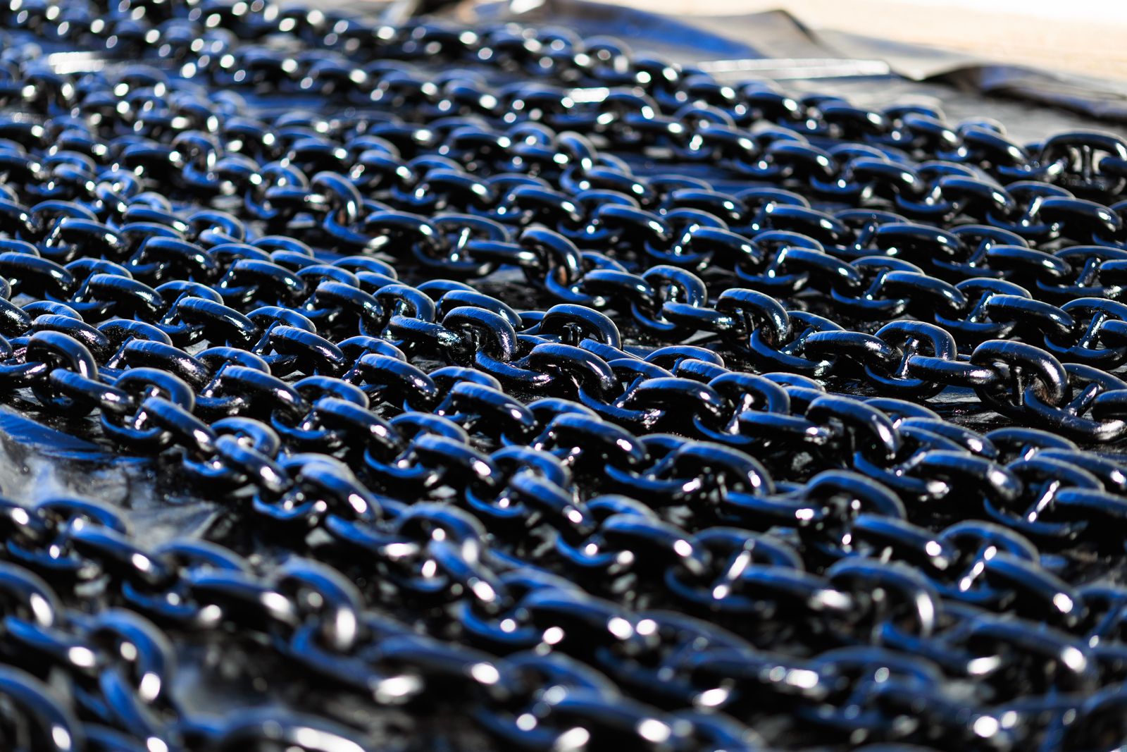 Eslabones de cadenas metálicas gruesas y brillantes apilados sobre una superficie oscura