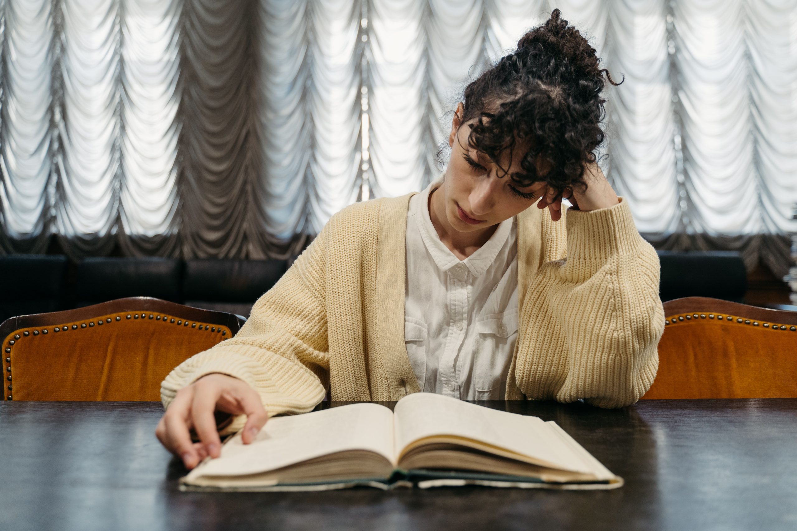 Persona leyendo un libro abierto junto a una ventana con luz natural