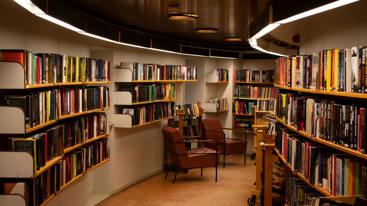 Un acogedor espacio de biblioteca en Estocolmo con sillones de cuero marrón y estanterías de madera llenas de libros.