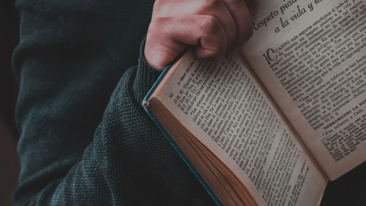 Una vista de cerca de una mano sosteniendo un libro español abierto, mostrando el texto en las páginas.